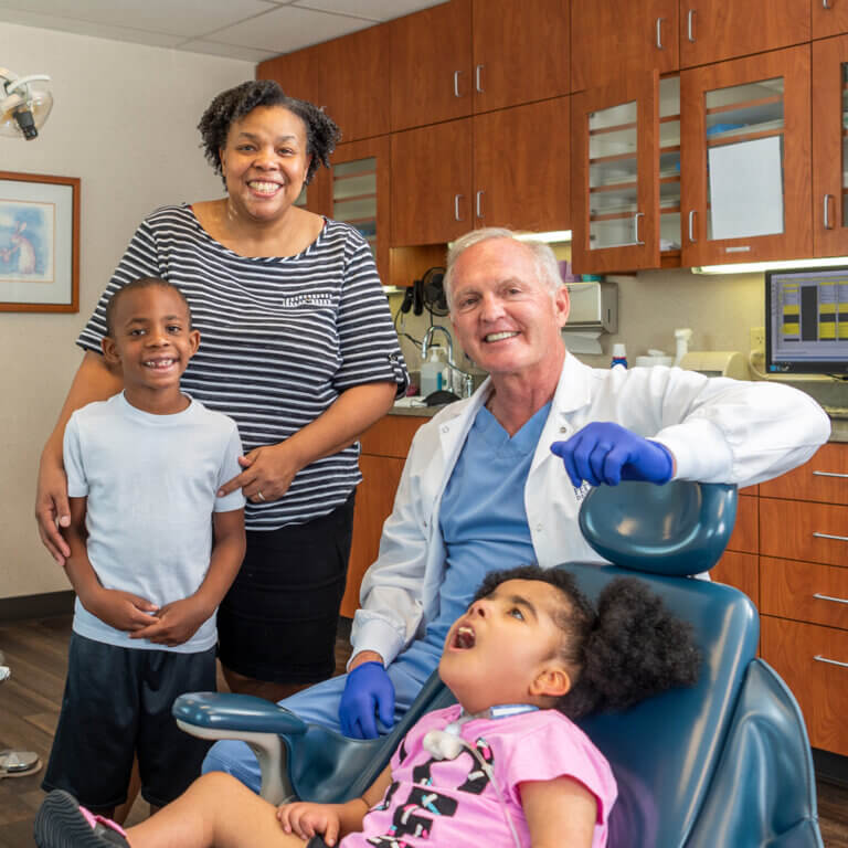 Dentist with young child . Family in the background