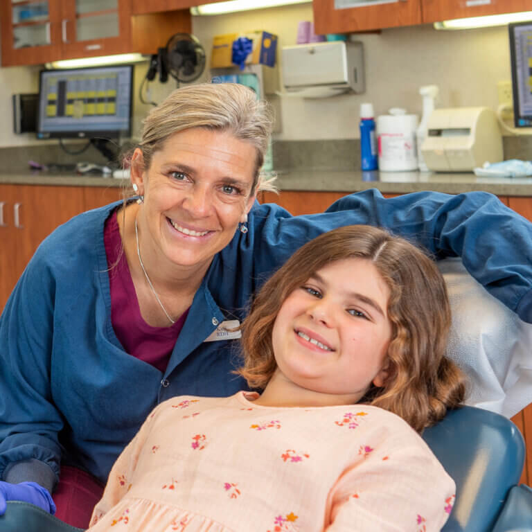 Dental assistant smiling with young teen girl