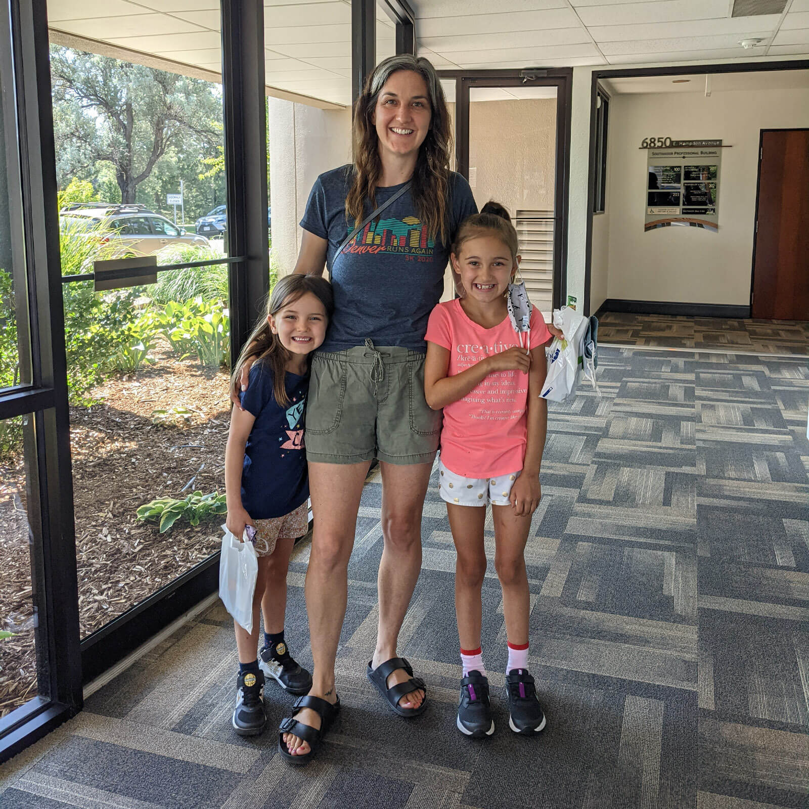 A mother with her two daughters standing in an entranceway